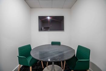 A conference room with a table and four chairs.